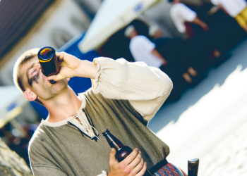 Opilec pije z lahve na ulici za bílého dne